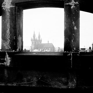View of a city through a weathered, arched opening.