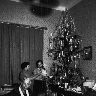 Family gathers around a table with a Christmas tree.