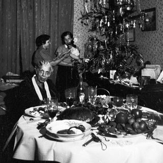 Family gathers around a table with a Christmas tree.
