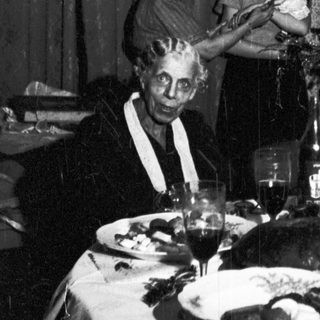Family gathers around a table with a Christmas tree.