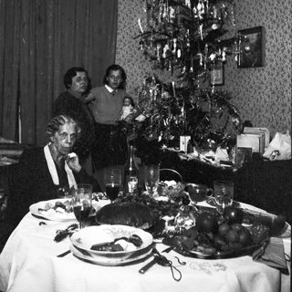 Family gathered for a festive meal near a Christmas tree.