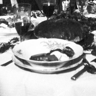 Family gathered for a festive meal near a Christmas tree.