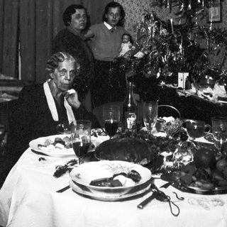 Family gathered for a festive meal near a Christmas tree.