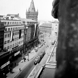 Black and white street scene with a tall tower in the distance.
