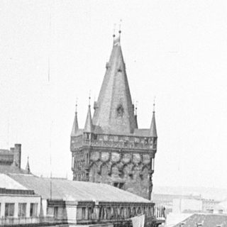 Black and white street scene with a tall tower in the distance.