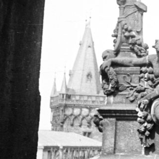 Statue and spire view through an arched stone structure.
