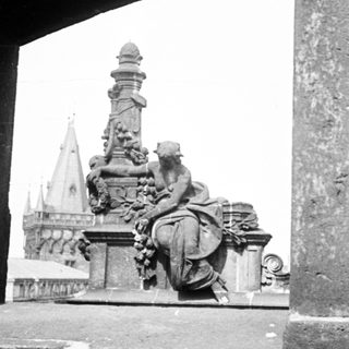 Statue and spire view through an arched stone structure.