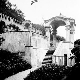 Monumental stone staircase and archway within a formal garden.