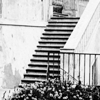 Monumental stone staircase and archway within a formal garden.