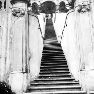 Monumental staircase ascends to an ornate, arched structure.