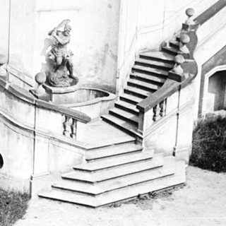 Ornate stone staircase leads down against a building facade.