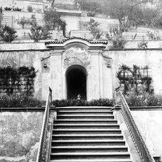 Stone staircase leads to an arched entrance and hillside.