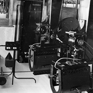 Vintage film projector stands in a room with equipment.
