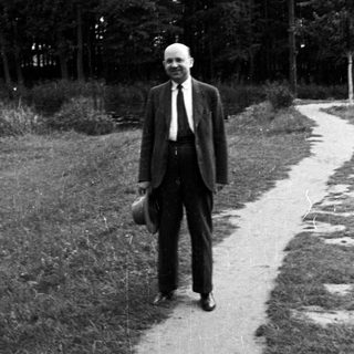 Man stands on a path in a wooded area.