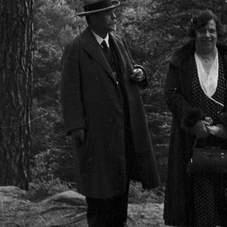 Three people pose near a castle in a wooded landscape.