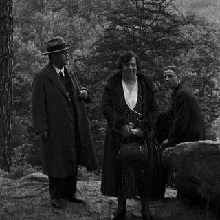 Three people pose near a castle in a wooded landscape.