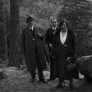 Three people stand before a castle, likely on a trip.