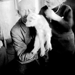 Man and child holding a lamb indoors.