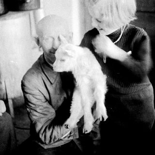 Man and child holding a lamb indoors.
