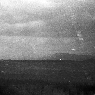 Monochromatic landscape with distant mountains and cloudy sky.