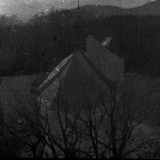 Church atop a hill, overlooking forested, distant mountains.