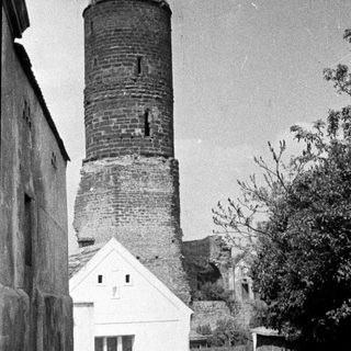 Men walk past a tower and building.
