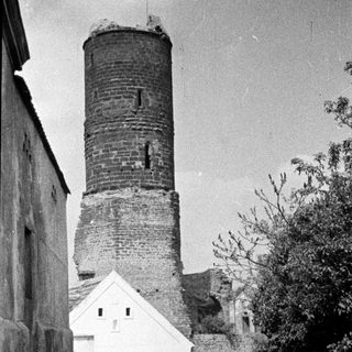 Men walk past a tower and building.