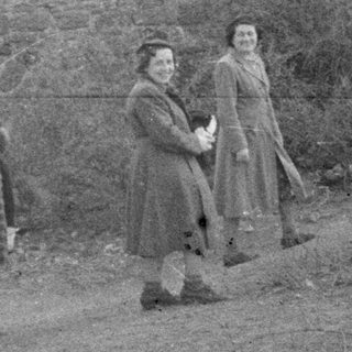 Group of people standing near a stone wall and door.