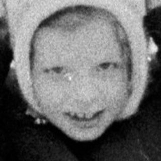 Child playing in snow, wearing a hat and coat.