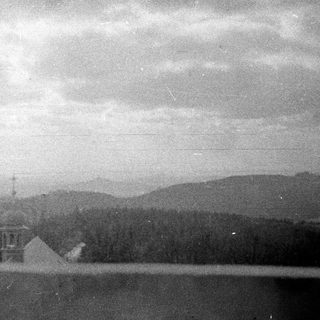 Church and forest landscape, visible across a body of water.