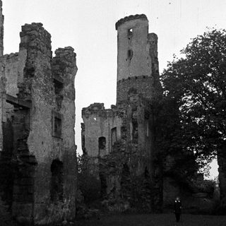 Ruined stone structure remains with trees and sky.