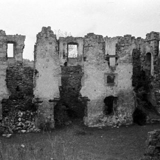 Ruined stone structure with visible windows and overgrown vegetation.