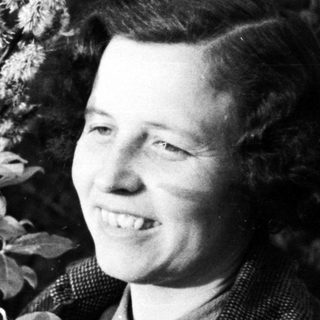 Woman smiles next to a willow tree in black and white.