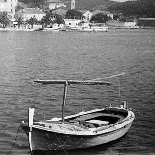 Here's a brief summary of the image: Boats moored in front of a coastal town.