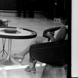 Couple relaxes in a lobby with a bar in the background.