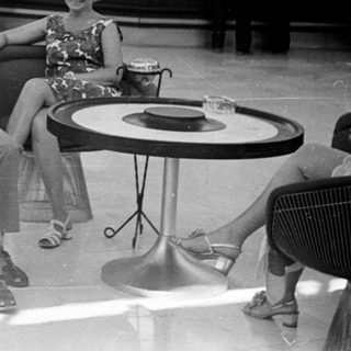 Couple relaxes in a lobby with a bar in the background.