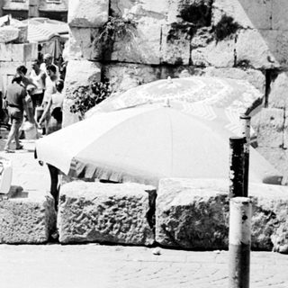 People walk past ancient ruins, a bustling street scene.