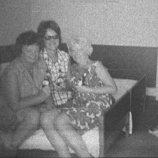 Here's a brief summary of the image: Two people seated on a bench, appearing relaxed.