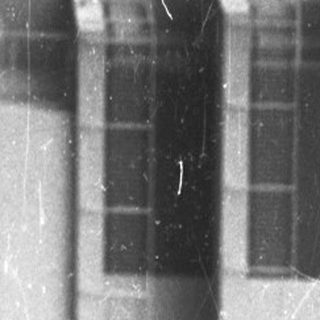 Black and white photo shows a building and a car.