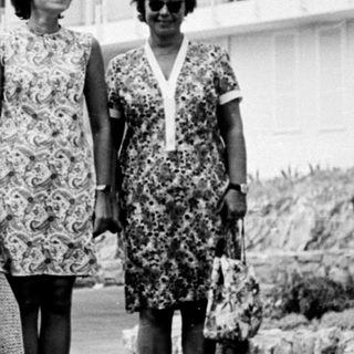 Three women stand in front of a hotel in the 1960s.