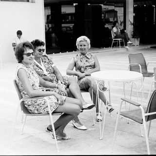 Two women sit at a table in a patio setting.