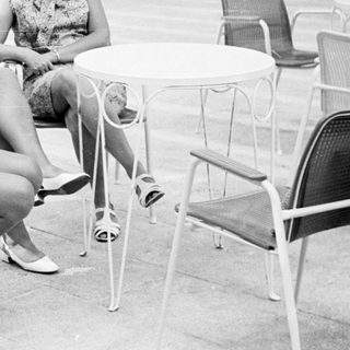 Two women sit at a table in a patio setting.