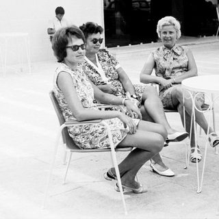 Two women sit at a table in a patio setting.