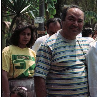 Family portrait outdoors with lush tropical foliage in background.