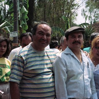 Family portrait outdoors with lush tropical foliage in background.