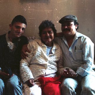Three people are sitting together on a sofa.
