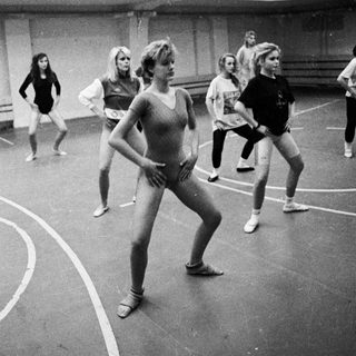 Ballet class in progress; dancers in a gymnasium.