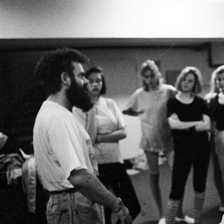 A man speaks to a group of women in a room.