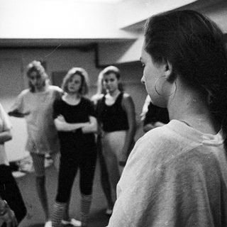 A man speaks to a group of women in a room.