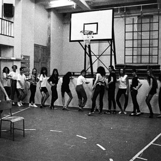 Black and white photo of a dance class in a gym.